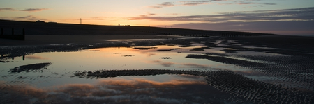 Beautiful sunrise panorama landscape reflected in pools on beach