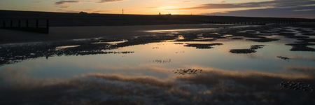 Beautiful sunrise panorama landscape reflected in pools on beach