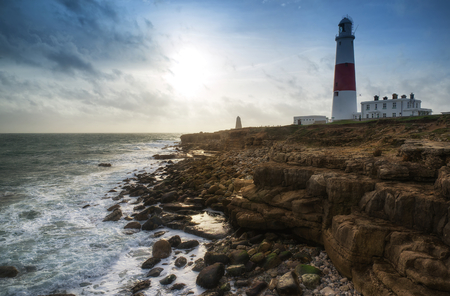 Seascape landscape of waves crashing onto rocks during beautiful Winter's day around lighthouseの写真素材
