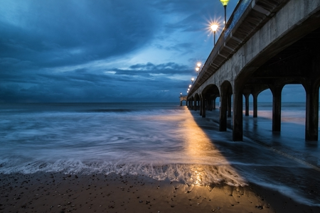 Twilight landscape of pier stretching out into sea with moonlight