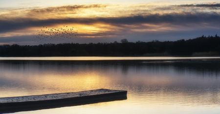 Beautiful sunrise landscape over lake with reflections and jettyの写真素材