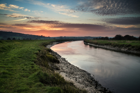 Beautiful vibrant sunrise reflected in calm river の写真素材