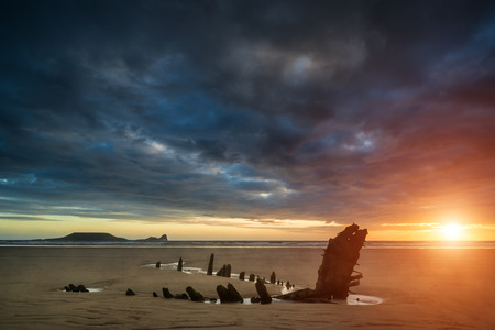 Dramatic sunset landscape over shipwreck on Rhosilli Bay beachの写真素材