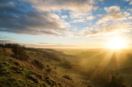 Beautiful sunrise over rolling countryside landscape in Autumnの写真素材