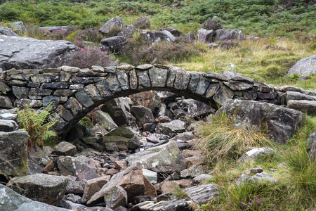 Old ancient packhorse bridge over mountain streamの写真素材