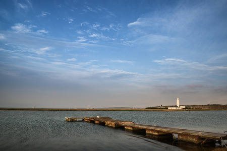 Landscape image large sky with jetty and lake with lighthouse in distanceの写真素材