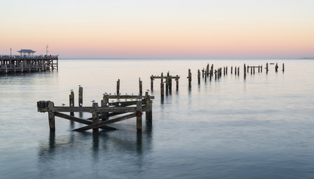 Beautiful calming long exposure landscape of ruined pier at sunsetの写真素材