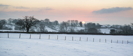 Beautiful sunrise landscape over snow covered Winter countryside