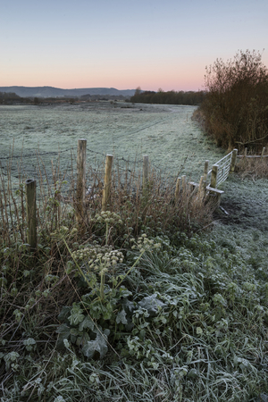 Winter sunrise landscape over river and fields covered in frostの写真素材