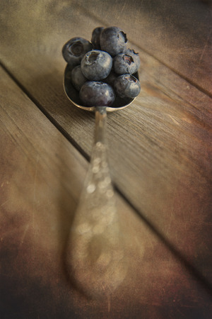 Blueberries in rustic setting with old wooden background with added texture filterの写真素材