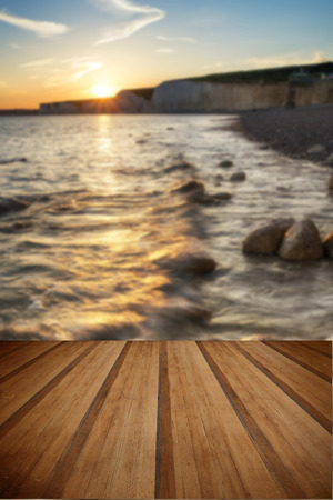 Beautiful landscape image of sunset over Birling Gap in England with wooden planks floorの写真素材