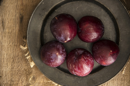 Fresh plums in natural light setting with moody vintage styleの写真素材