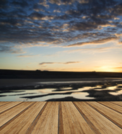 Beautiful sunrise reflected in low tide water pools on beach landscape with wooden planks floorの写真素材