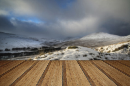 Beautiful landscape of snow covered mountain range during late afternoon in Winter with wooden planks floorの写真素材
