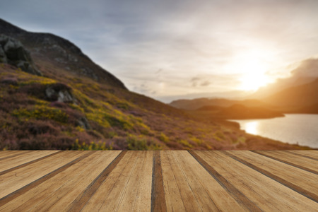 Stunning Summer sunrise over mountain range with lake and beautiful sky with wooden planks floorの写真素材
