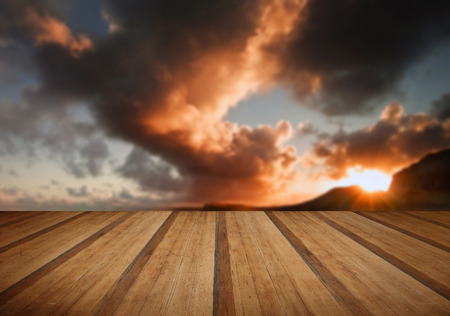 Sunrise and mountains refelcted in sea with wooden planks floorの写真素材