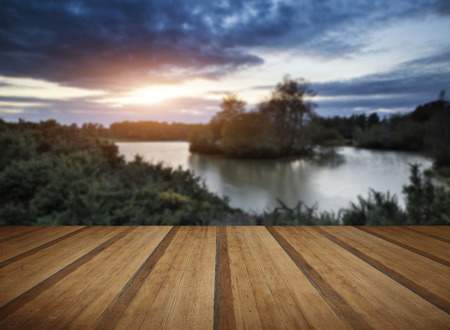 Beautiful Autumn sunset over lake landscape in forest with wooden planks floorの写真素材