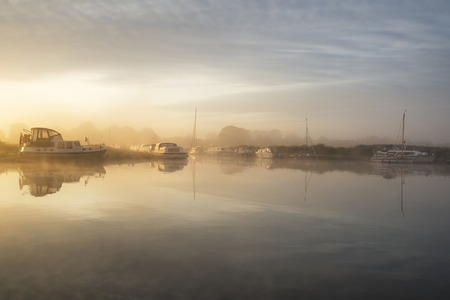 Stunning foggy sunrise over peaceful river landscape in English countrysideの写真素材