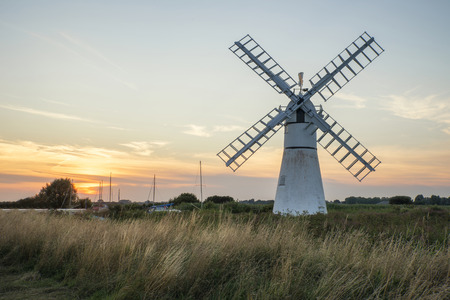 Stunning landscape of windmill and river at sunrise on Summer morningの写真素材