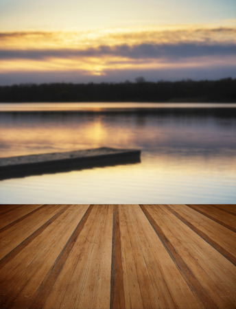 Beautiful sunrise landscape over lake with reflections and jetty with wooden planks floorの写真素材