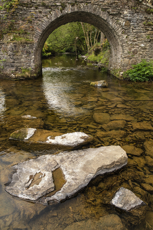 Landscape image of old medieval bridge in river setting in English countryside