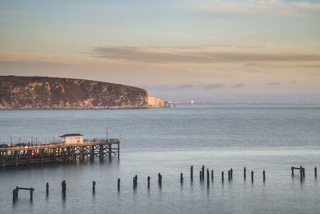 Long exposure landscape image of colorful sunrise over ocean and derelict pier in distanceの写真素材