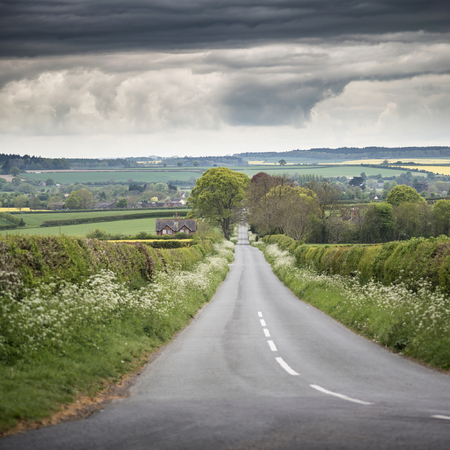 Landscape image of empty road in English countryside with stormy sky overheadの写真素材