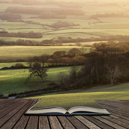 Beautifiul late Winter evening sunlight raking across English countryside landscape concept coming out of pages in open bookの写真素材