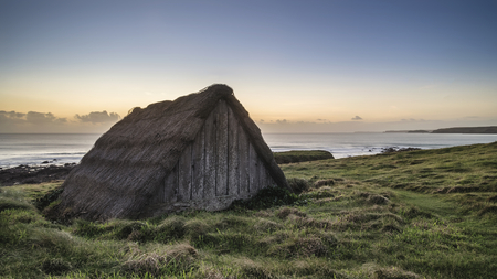 Beautiful sunset landscape image of seaweed drying hut at Freshwater West beach on Pembrokeshire Coast in Walesの写真素材