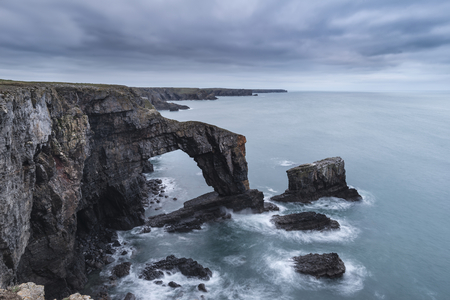 Beautiful sunset landscape image of Green Bridge of Wales on Pembrokeshire Coast in Walesの写真素材