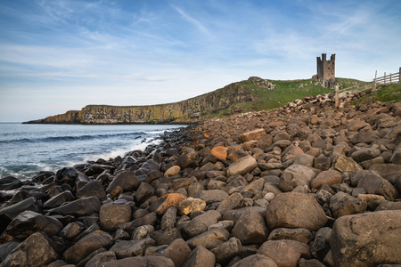 Beautiful landscape image of Dunstanburgh Castle on Northumberland coastline in England during late Spring eveningの写真素材