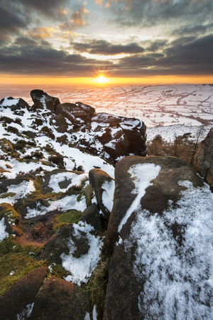 Winter sky over snow covered Winter landscape in Peak District at sunsetの写真素材