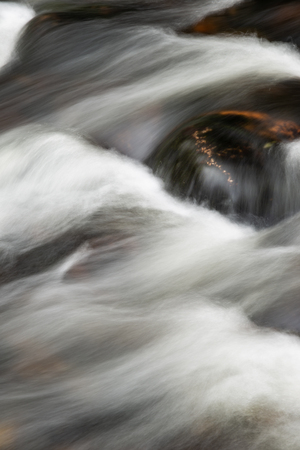 Detail landscape image of river flowing over rocks with long exposure motion blur