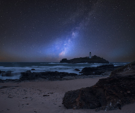 Stunning vibrant Milky Way composite image over landscape of Godrevy lighthouse on Cornwall coastline in Englandの写真素材