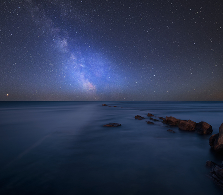 Stunning vibrant Milky Way composite image over landscape of Beautfiul long exposure of sea over rocksの写真素材