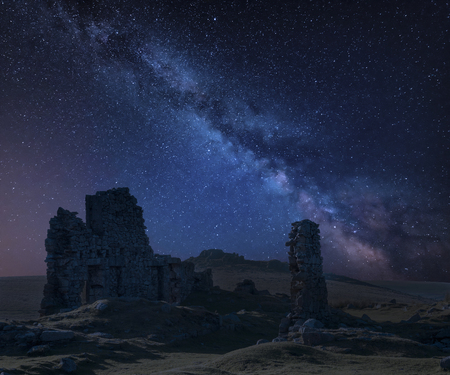 Stunning vibrant Milky Way composite image over abandoned Foggintor Quarry in Dartmoor with raking soft sunlight over ruins and derelict buildingsの写真素材