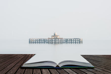 Fine art minimalist landscape image of derelict pier remains at sea during foggy morning giving appearance of ruins floating coming out of pages of open story bookの写真素材