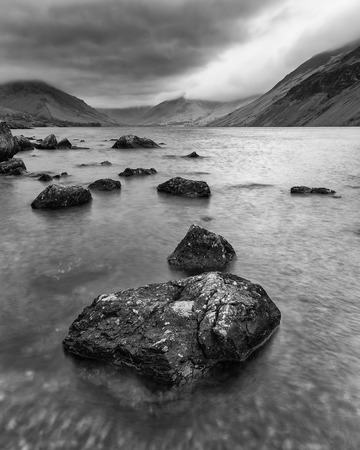 Beautiful long exposure landscape image of Wast Water in UK Lake District during moody Spring evening in black and whiteの写真素材