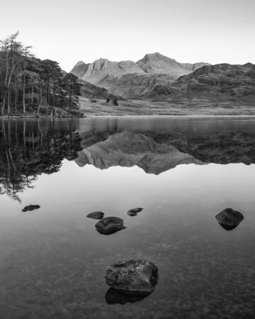 Stunning Autumn Fall vibrant sunrise over Blea Tarn in the Lake District with High Raise and The Langdales in the distanceの写真素材