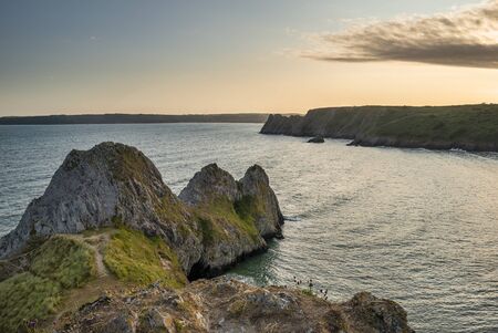 Beautiful Summer evening sunset beach landscape image at Three Cliffs Bay in South Wales