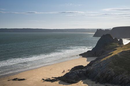 Beautiful Summer evening sunset beach landscape image at Three Cliffs Bay in South Wales