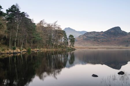 Stunning Autumn Fall vibrant sunrise over Blea Tarn in the Lake District with High Raise and The Langdales in the distanceの写真素材