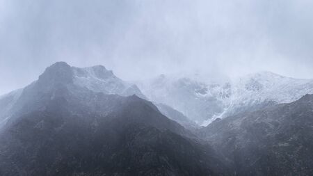 Stunning moody dramatic Winter landscape mountain image of snowcapped Y Garn in Snowdoniaの写真素材