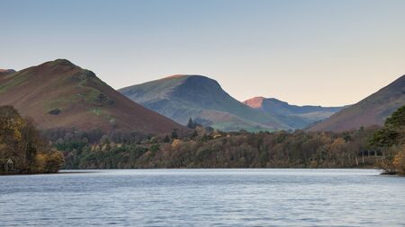 Beautiful long exposure landscape image of Derwent Water in Lake District during Autumn Fall sunrise with soft pastel colorsの写真素材