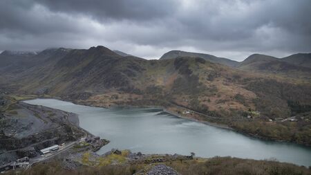 Stunning landscape image of Dinorwig Slate Mine and snowcapped Snowdon mountain in background during Winter in Snowdonia with Llyn Peris in foregroundの写真素材
