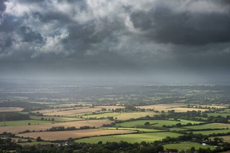 Beautiful Summer landscape image of escarpment with dramatic storm clouds and sun beams streaming...