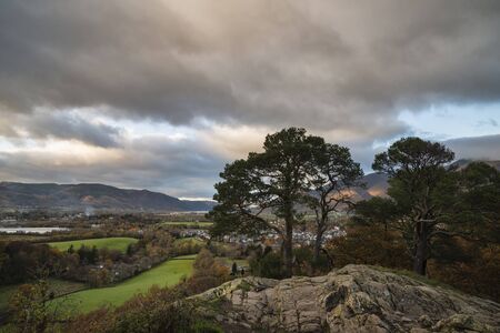 Epic Autumn Fall landscape image of view from Castlehead in Lake District towards Skiddaw at sunset with beautiful lighting in skyの写真素材