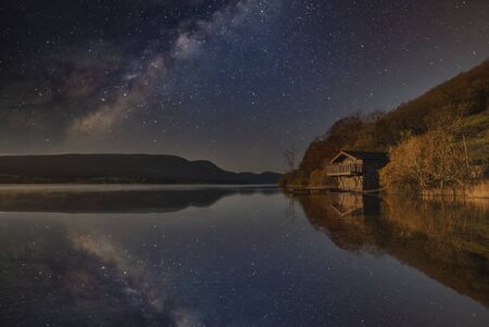 Beautiful epic digital composite landscape of Milky Way over Ullswater in Lake Districtの写真素材