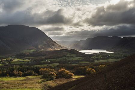 Epic sun beams light up Crummock Water in dramatic Autumn Fall landscape image with Mellbreak and Grasmoorの写真素材
