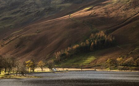 Stunning epic Autumn Fall landscape Buttermere in Lake District with beautiful early morning...